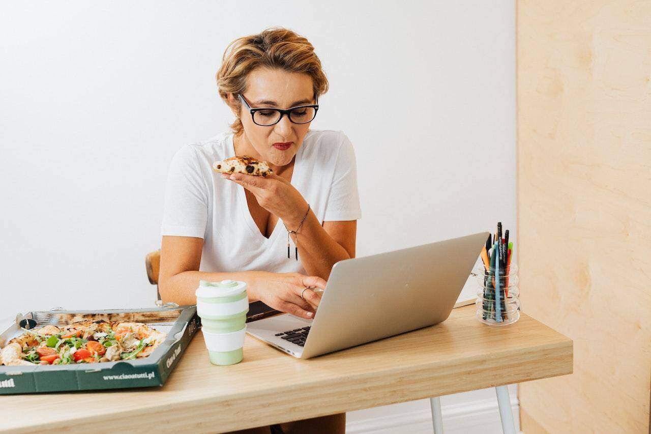 kobieta jedząca oraz przeglądająca internet