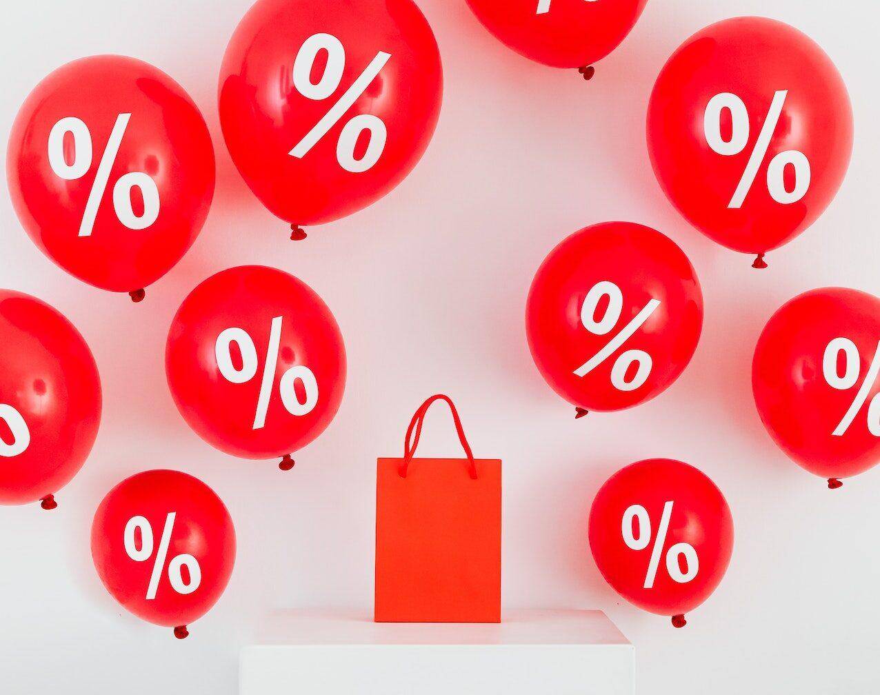 torba na zakupy oraz balony z procentami oznaczające promocję 